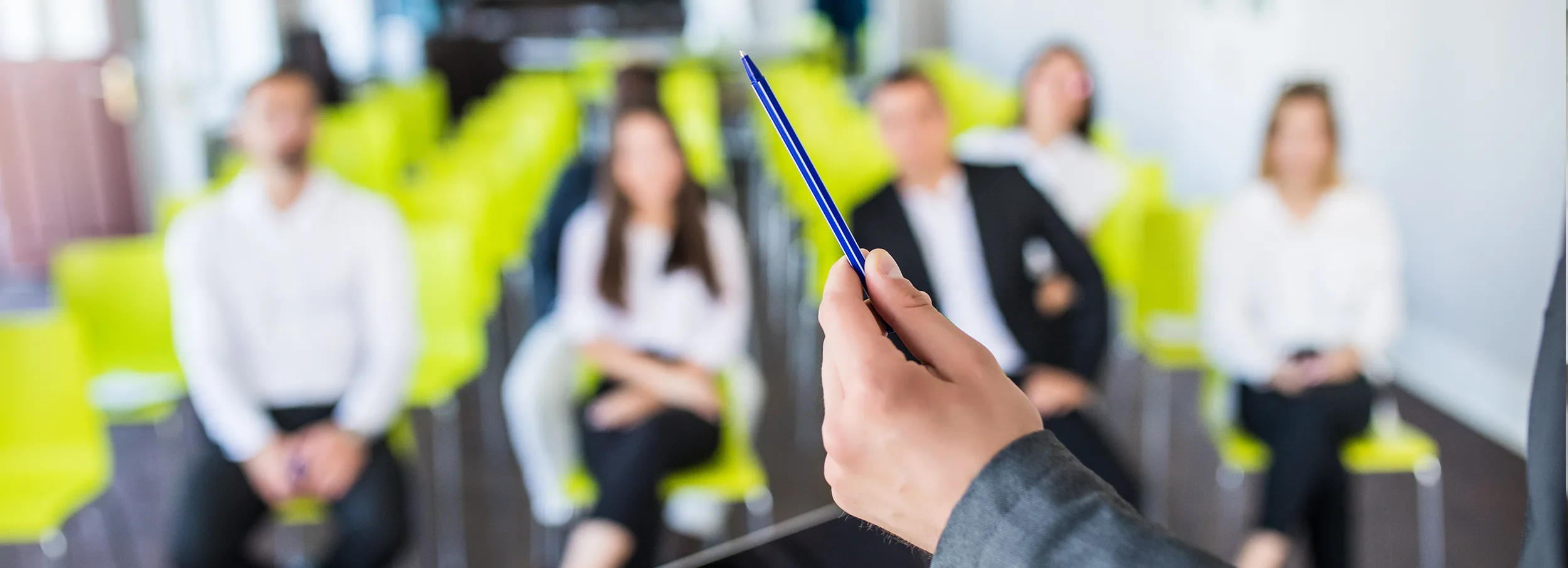 Close up of person holding pen, trainees in background